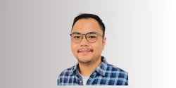 Seorang pria mengenakan kemeja kotak-kotak sedang berpose di depan latar belakang polos. Fokus pada penampilan dan gaya berpakaian yang santai.